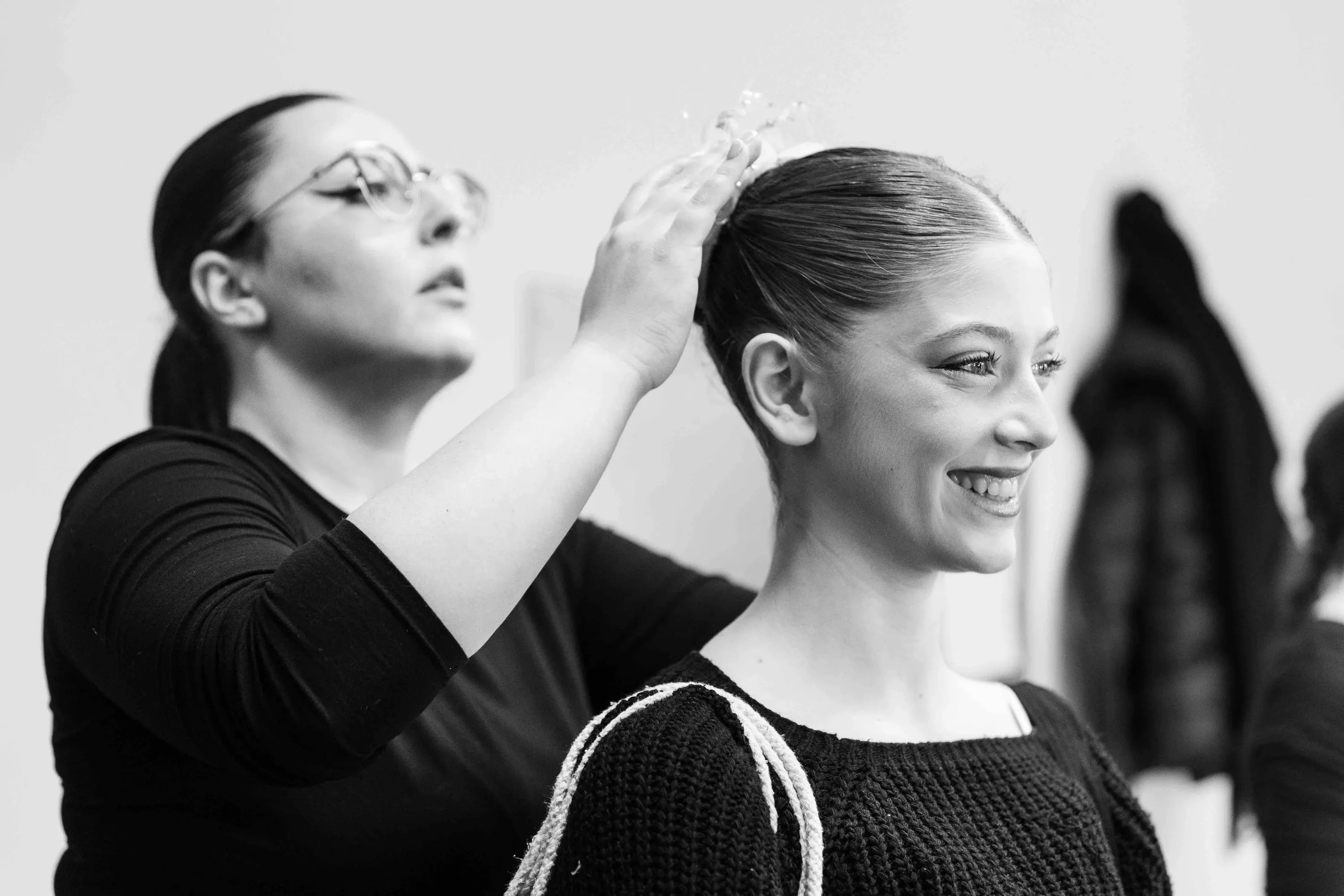 Una ballerina sorride mentre le sistemano l'acconciatura