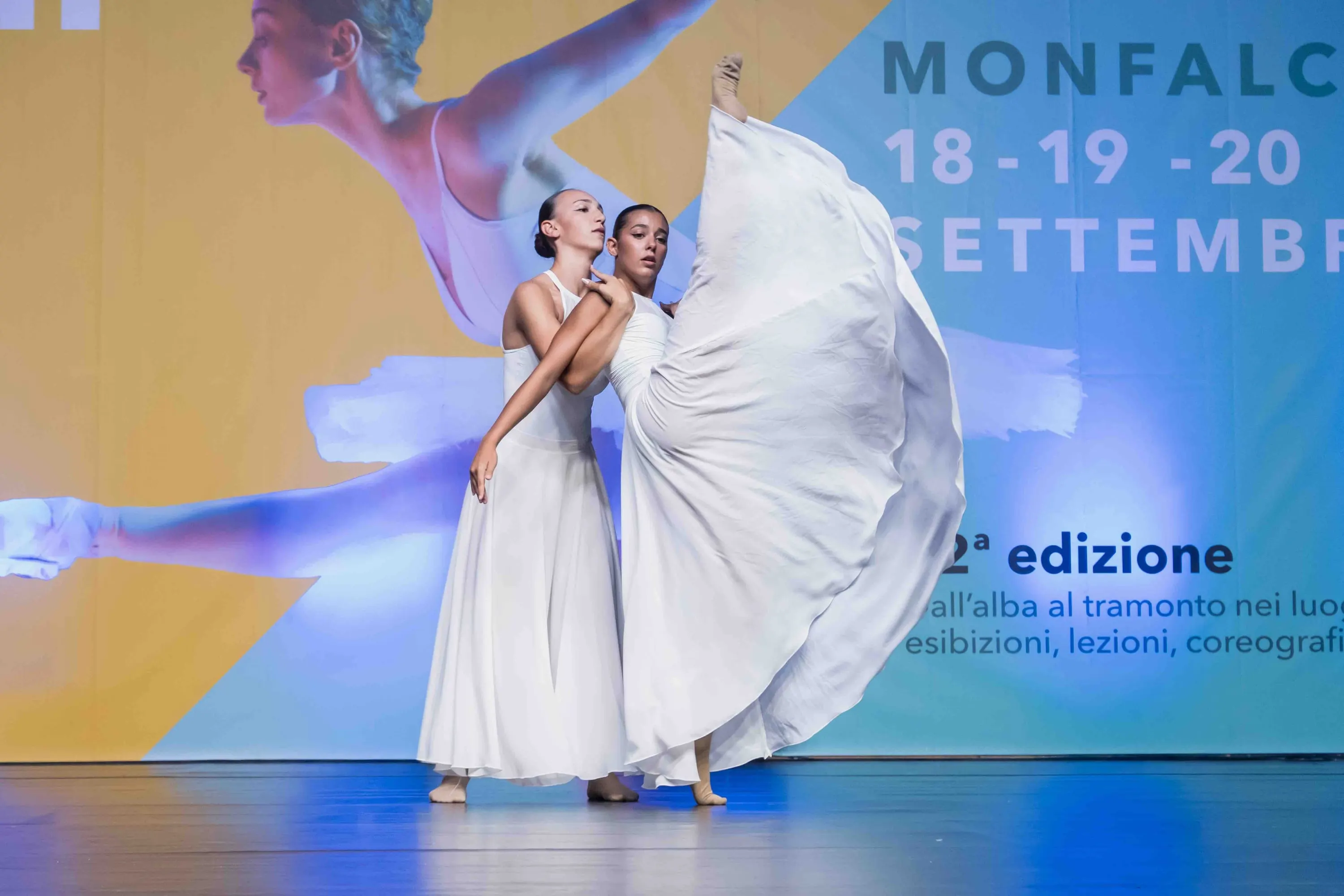 Due danzatrici in abiti bianchi, una gonna sollevata come un'ala