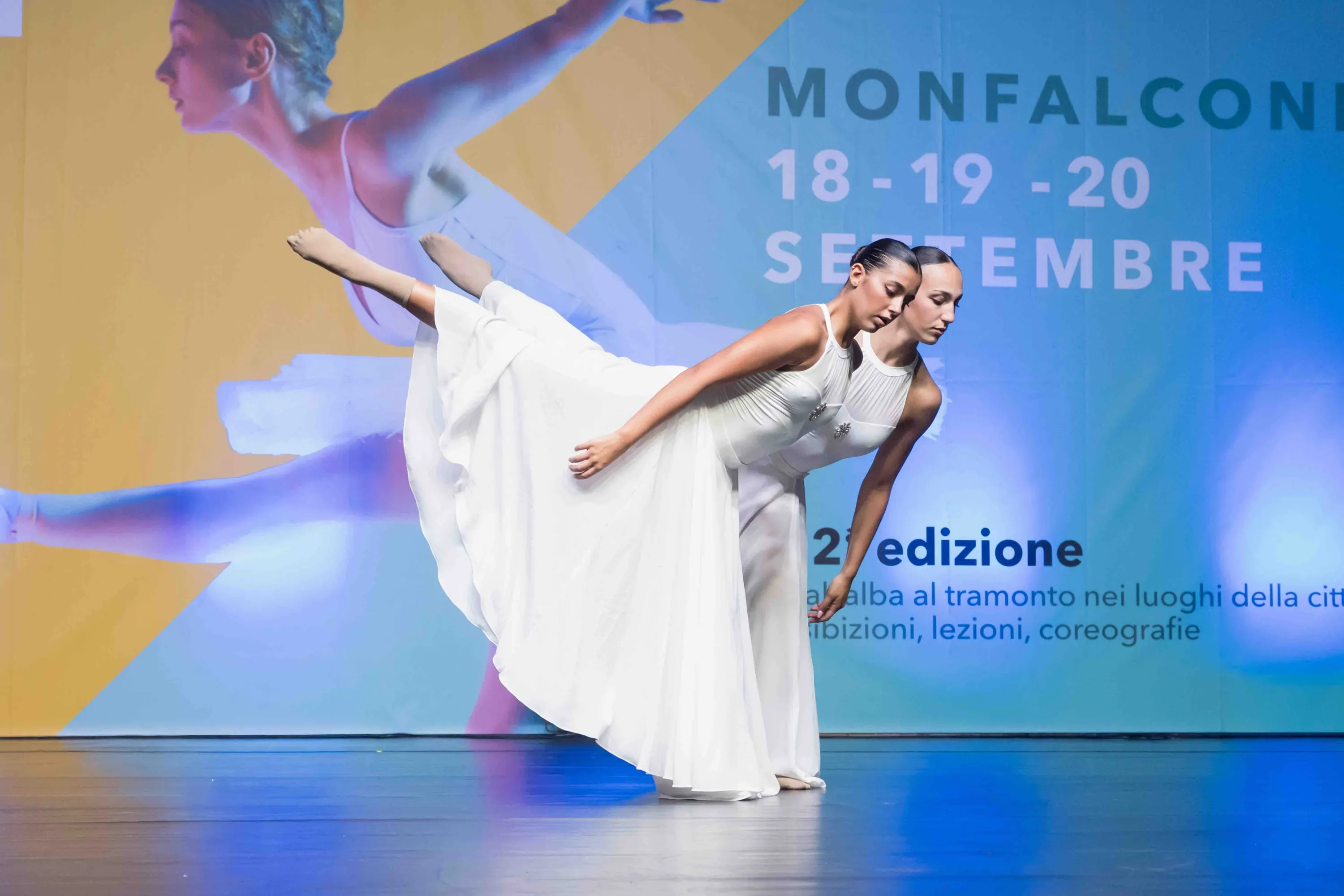 Una danzatrice in abito bianco in arabesque