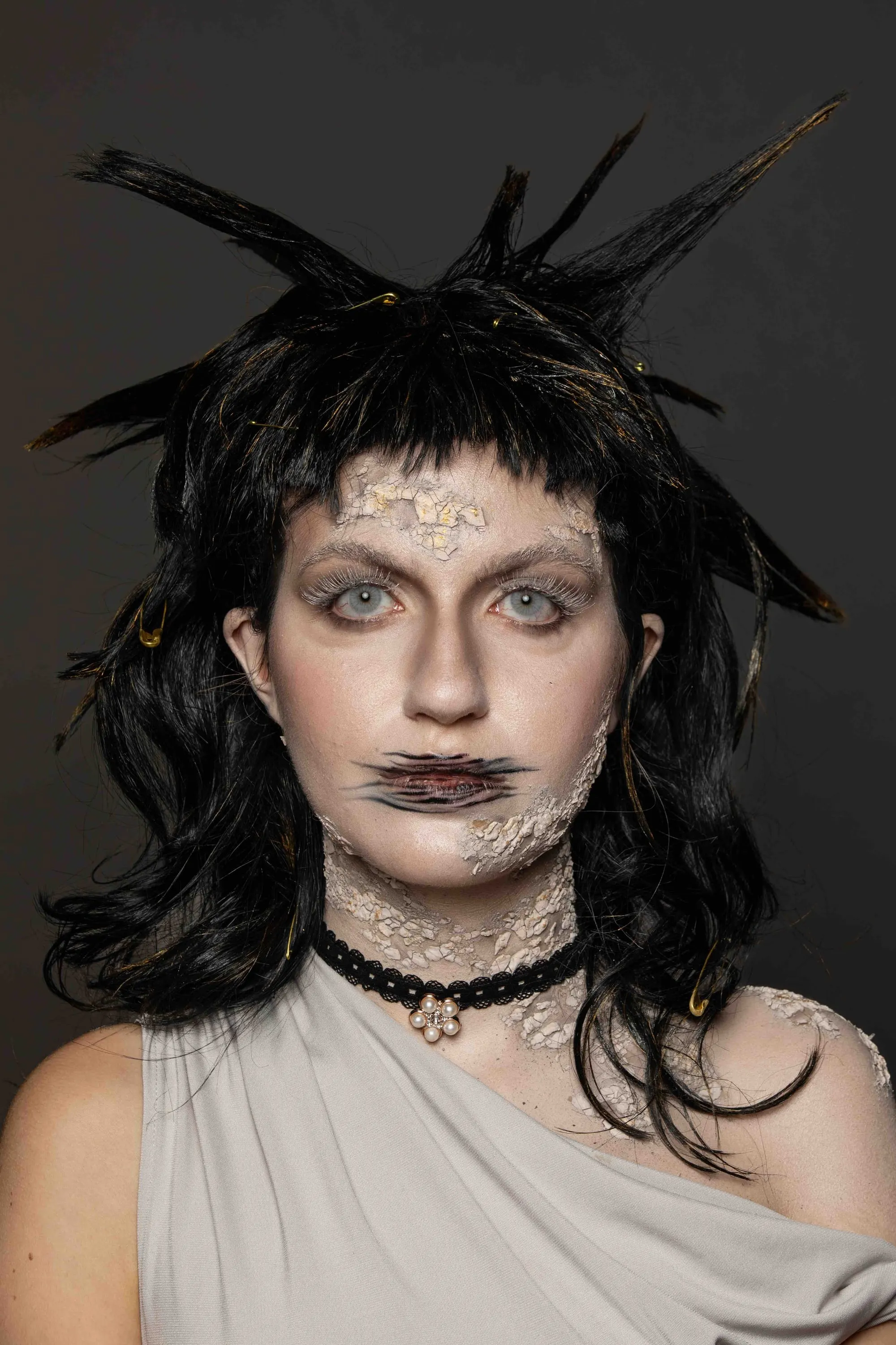 Trucco teatrale con parrucca nera a piume e labbra cucite