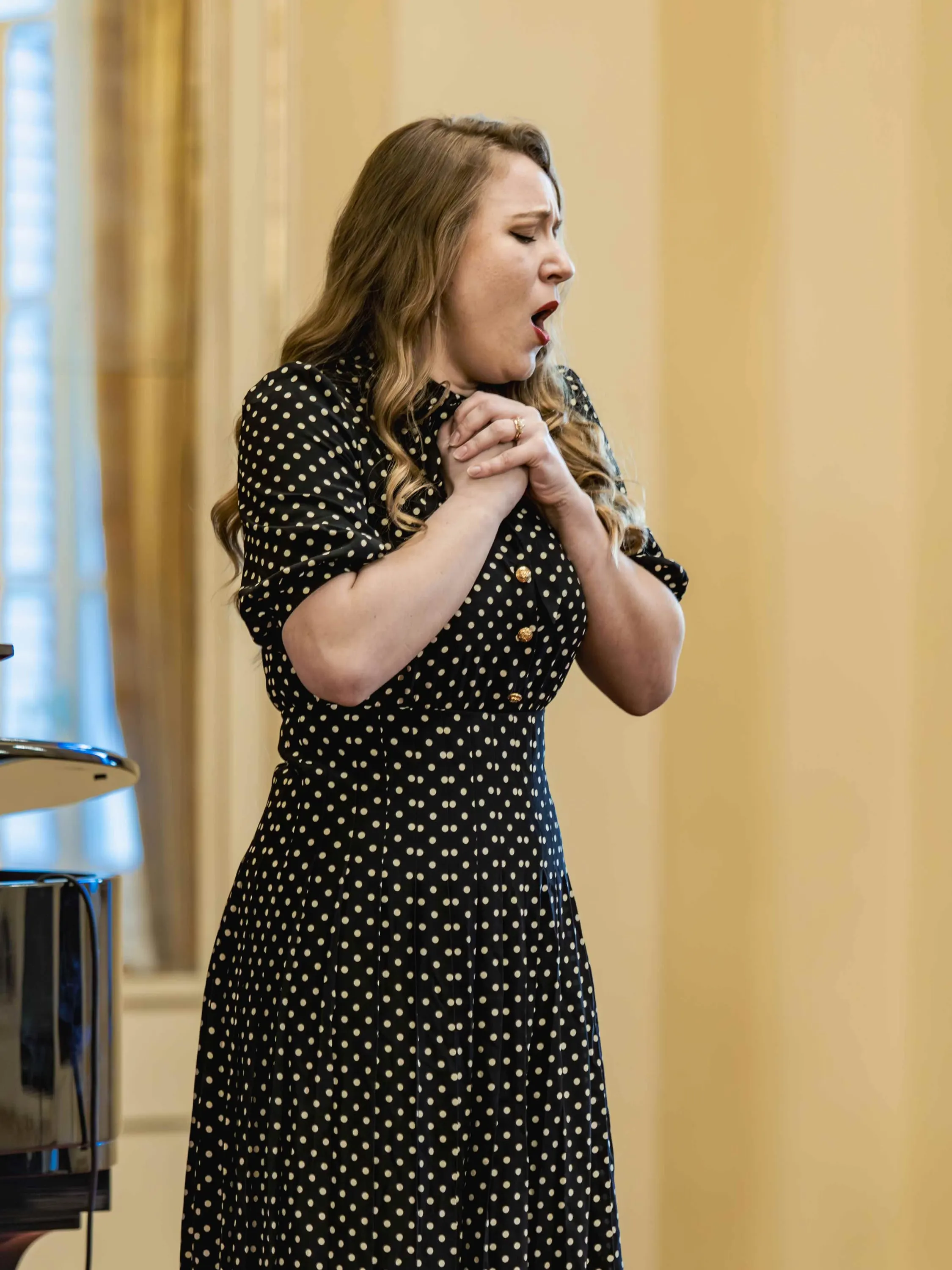 Una soprano canta con le mani giunte